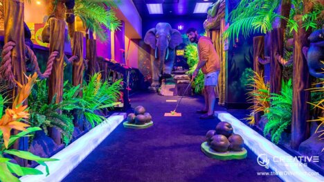 man playing mini golf in a dark mini golf room which is lit up with bright colours